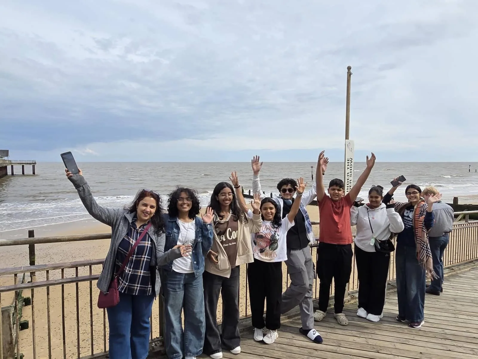GoldenBee students waving on the beach boardwalk during the UK immersion programme