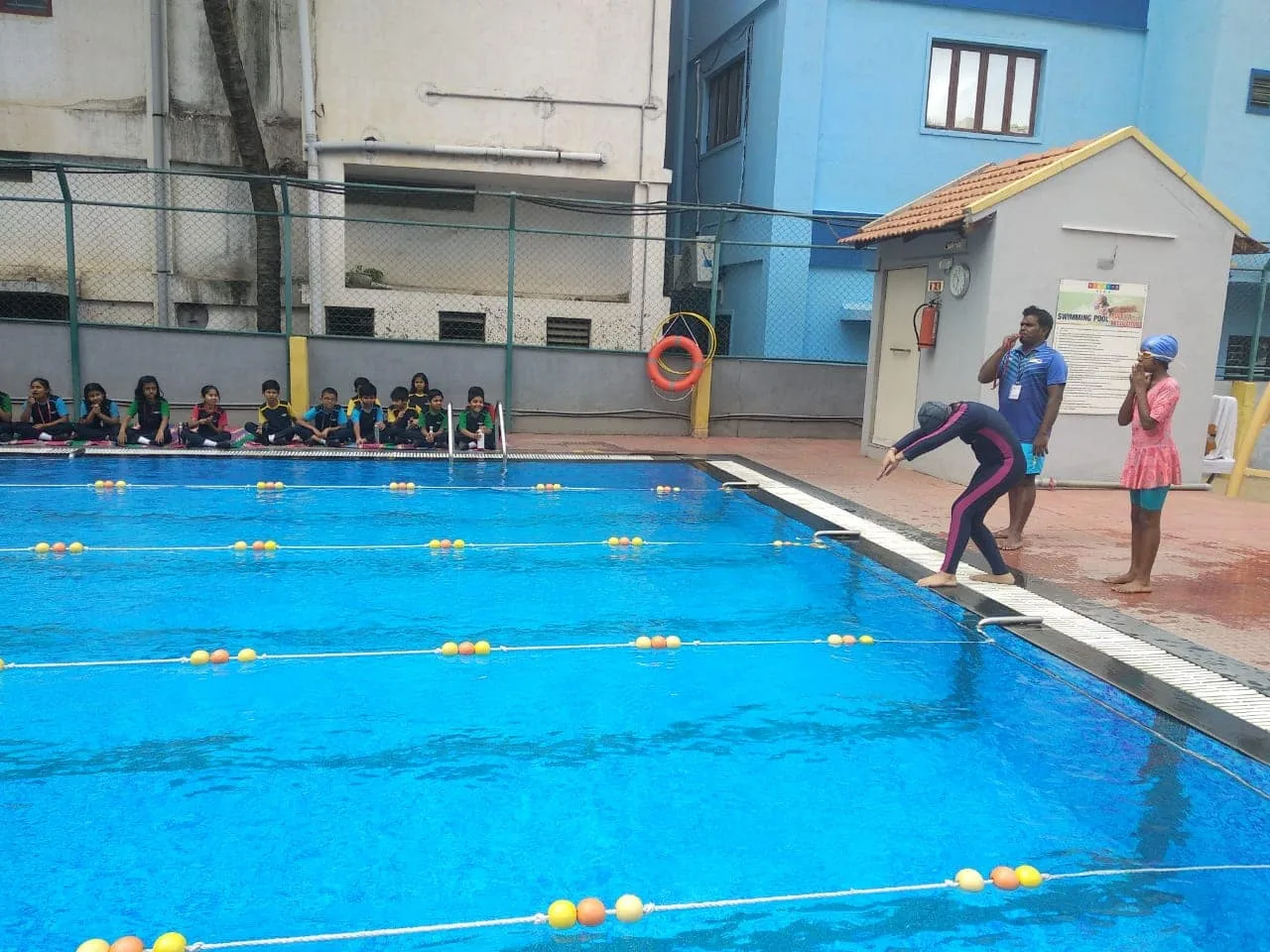 A coach guiding GoldenBee students during a swimming session